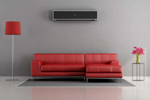 Planning to Remodel? Go Ductless! Living room with red sofa and ductless air conditioner.