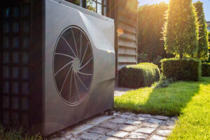 Transitioning Your Heat Pump Use Between Seasons. Close-up of black full inverter heat pump outside in the garden.